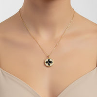 Gold clover pendant necklace on a thin chain, black enamel charm at collarbone