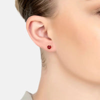 Red ruby heart stud earring on gold post, worn on ear