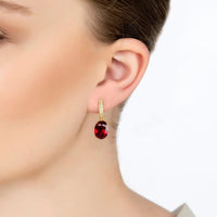 Gold hoop-style drop earrings with oval dark red gemstone and crystal accents