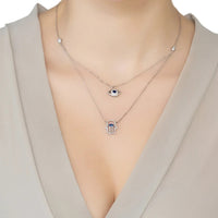 Silver layered charm necklace on model: evil eye and hamsa with two chains