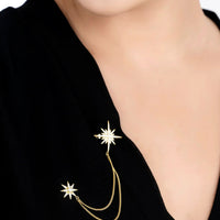 Gold starburst brooch with pin, dangling chains and star accents