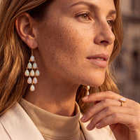 Close-up of silver opal teardrop chandelier earrings with dangling drops and hook backs.