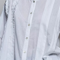 Ivory lightweight woven shirt close-up: ruffle-trim round neck and button placket