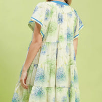 Floral babydoll dress back view with blue contrast trim and tiered skirt on cream