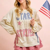 Cream sweatshirt with blue star lettering, red stripe graphic, and bow patch details.