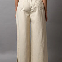 Cream wide-leg drawstring pants with distressed hems and relaxed straight legs