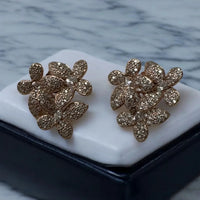 Gold-tone sparkling floral stud earrings with petal cluster design