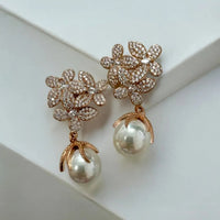 Gold rhinestone flower earrings with white pearl drop, angled close-up