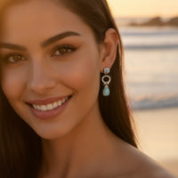 Turquoise teardrop drop earrings on model, silver-tone with black enamel ring and studs