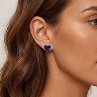 Heart-shaped sapphire-blue stud earring on ear with silver back