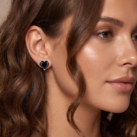Heart stud earrings with black gemstone, worn on model ear