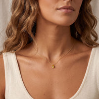 Gold teardrop necklace with small yellow citrine pendant worn on a chain