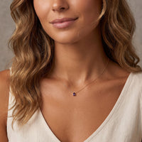 Gold teardrop gemstone pendant necklace worn on a neckline