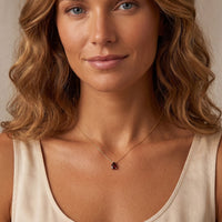 Gold chain necklace with small red teardrop gem pendant