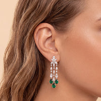 Silver chandelier earrings with green teardrop drops and crystal detailing at ear