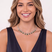 Gold necklace with emerald teardrop stones, worn at V-neckline