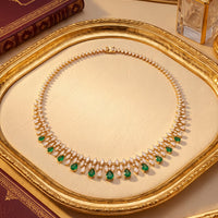 Gold necklace with emerald teardrop stones and sparkle rhinestone band, close-up