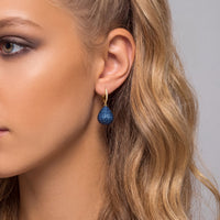 Pear drop sapphire blue gemstone earring with gold hook on model ear