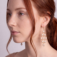 Pearl drop chandelier earrings on gold hooks, worn by model