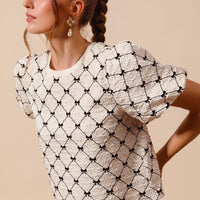 Ivory woven bubble sleeve top with black bow texture pattern, side view