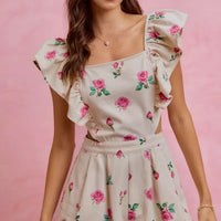 Ivory floral romper with ruffled cap sleeves and gathered waist, pink rose print