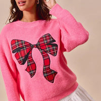 Pink ribbed sweater with oversized red plaid bow graphic and long sleeves