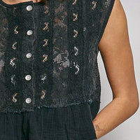 Black lace sleeveless top close-up: round neck, button placket, and ruffle hem