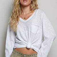 Off white V-neck knit top with contrast hand-stitched trim and chest pocket, knotted front.
