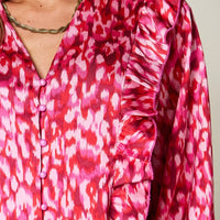 Hot pink printed blouse close-up showing button placket and ruffled shoulder trim