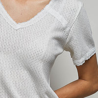 Off-white textured V-neck short-sleeve t-shirt close-up, scalloped lace trim