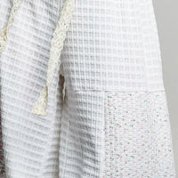 Ivory patchwork knit pants close-up: textured fabric panels and speckled side panel