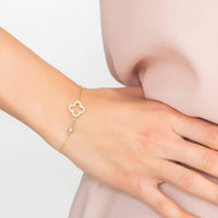Gold open clover charm bracelet on wrist with adjustable chain