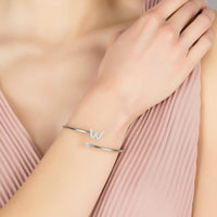 Silver initial W bangle on wrist with slim cuff and small stone accents