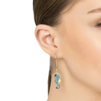 Turquoise seahorse drop earrings with gold-tone hook, close-up on side of face