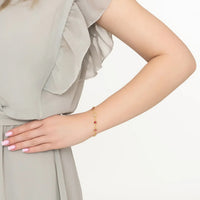 Gold bracelet on wrist with pink and gray oval stones and chain links