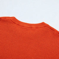 Orange knit sweater with ribbed crew neck and textured stitch pattern, long sleeves