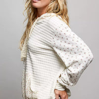 Cream knit hoodie with floral print sleeves and kangaroo pocket, side view