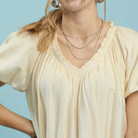Cream mini shift dress close-up with V-neck ruffles and short puff sleeves.