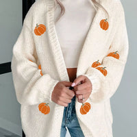 Cream knit cardigan with orange pumpkin embroidery accents and ribbed cuffs.