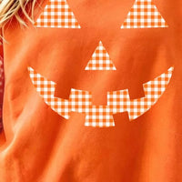 Close-up orange sweatshirt with checkered plaid pumpkin face graphic