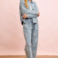 Light blue washed denim jacket with white floral print, button front and side pockets