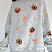 Light gray Halloween sweatshirt with orange sequin pumpkin face and bow patterns