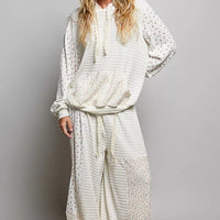 Cream knit hoodie with floral print sleeves and kangaroo pocket, front view