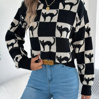 Side-front view: black and cream ghost checkerboard knit sweater with ribbed hem