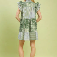 Green patchwork tiered dress with striped yoke, flutter sleeves, and dotted skirt.