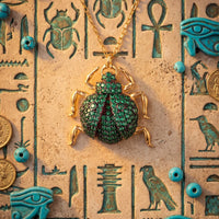 Green scarab pendant in a gold-tone setting with small turquoise beads