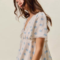 Ivory blouse with blue dot print, tie-front V-neck, and flutter sleeves.