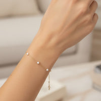 Gold pearl bracelet on wrist with small round white pearls and chain links