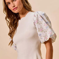 White ribbed sweater top with pastel floral puff sleeves and scalloped bottom edge