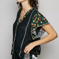 Black V-neck blouse with ruffle sleeves and floral print trim, side view